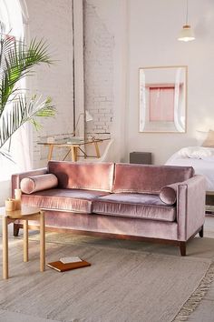 a living room with a pink velvet couch and coffee table