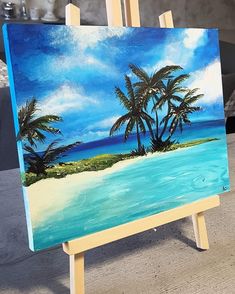 an easel with a painting of palm trees on the beach