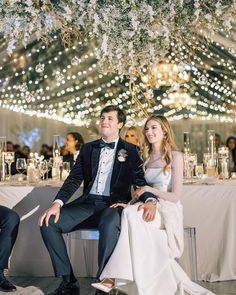 a bride and groom sitting on a bench in front of a chandelier