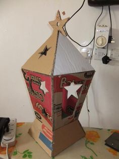 a cardboard box shaped like a house with stars on the top and sides, sitting on a table