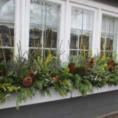 the window sill is decorated with evergreen, pine cones and other greenery on it