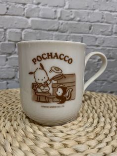 a coffee cup with the words pochaco on it sitting on a wicker table