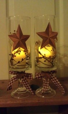 two wine glasses with candles in them on a table