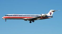 an american airlines jet flying in the sky with it's landing gear extended out