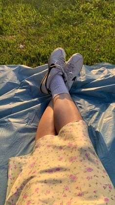 a person laying on top of a blue tarp in the grass with their legs crossed