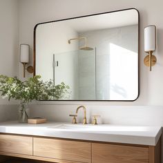 a bathroom sink with a large mirror above it and flowers in a vase on the counter