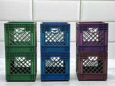 three different colored crates sitting next to each other on a white counter top in front of a tiled wall