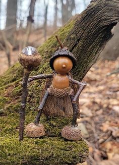 a small wooden figure sitting on top of a moss covered tree