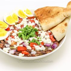 a white bowl filled with beans, eggs and other food on top of a table