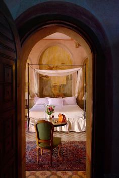 an archway leading to a bedroom with a bed and chair in it's center