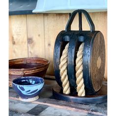 an old fashioned wooden device with rope on it's handle and bowl next to it