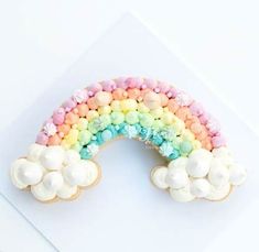 a rainbow shaped cookie with marshmallows and candy on it's side