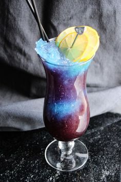 a purple and blue drink with lemon wedges in it