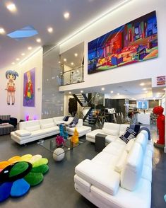 a large living room with white couches and art on the wall above it's fireplace