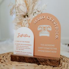 two business cards sitting on top of a wooden stand next to a vase with flowers