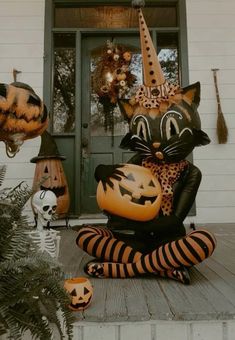 an inflatable cat sitting on the front porch with pumpkins and jack - o'- lanterns