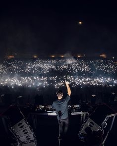 a man standing on top of a stage with his arms in the air and lights behind him