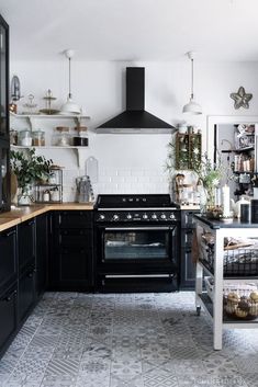 a black and white kitchen with an oven in the middle, shelves on the wall