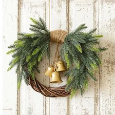 a christmas wreath with two bells hanging from it