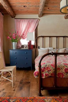 a bed room with a neatly made bed and a flower vase on the end table