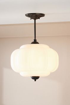 a light fixture hanging from the ceiling in a room with white walls and flooring