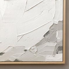 an abstract painting with white paint and brown frame on the wall in front of it