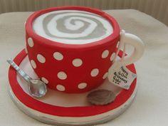 a red and white polka dot coffee cup cake with spoons on the plate next to it