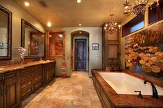 a large bathroom with two sinks, tub and chandelier hanging from the ceiling