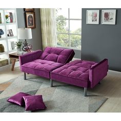 a purple couch sitting on top of a rug in a living room next to a window