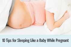 a pregnant woman laying on top of a bed under a white comforter and pillows