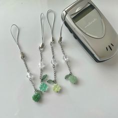 three green and white dangling earrings next to an mp3 player