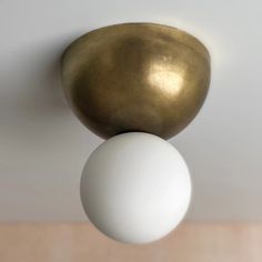 two white and gold balls are hanging from the ceiling in front of a light fixture