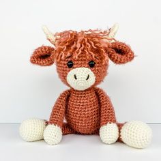 a crocheted brown cow sitting next to a white wall