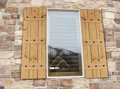 a window with wooden shutters on a stone wall