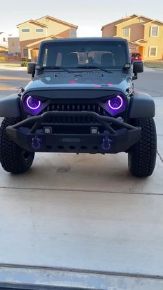 a black jeep with purple lights on it's front bumper is parked in the driveway