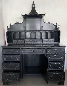 an old black desk with drawers and a mirror