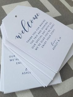 four white tags with the words welcome on them sitting on top of a tablecloth