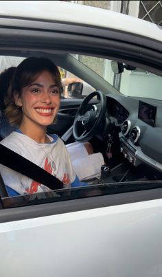 a woman sitting in the driver's seat of a car smiling at the camera