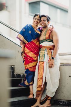 a man and woman standing on the steps in front of an escalator with their arms around each other