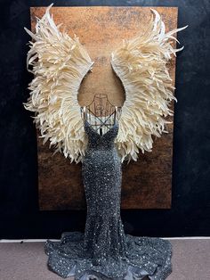 a dress made out of feathers is displayed in front of a painting