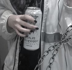 a woman with black nail polish holding a can of beer in her hand and chain around her neck