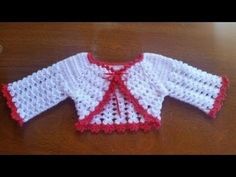 a crocheted baby sweater sitting on top of a wooden table