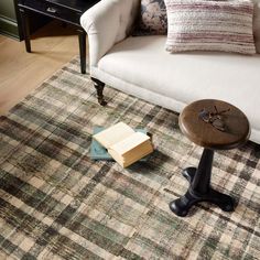 a living room area with a couch, coffee table and book on the floor in front of it