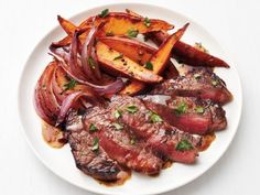 steak, potatoes and carrots on a white plate with garnishes in the middle