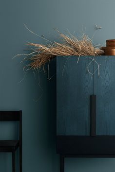 a wooden cabinet with some dry grass on top