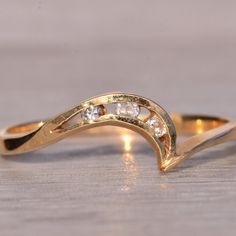 a yellow gold ring with three diamonds on the inside and outside, sitting on a wooden surface