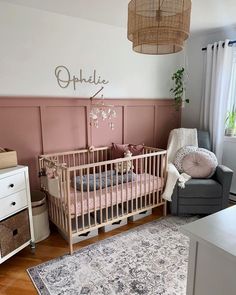 a baby's room with pink walls and white furniture, including a crib