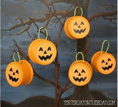 four pumpkins hanging from a tree with jack - o'- lantern faces on them