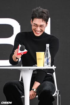 a man sitting at a white table with a bottle