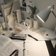 the desk is cluttered with papers, pens, and a lamp on top of it